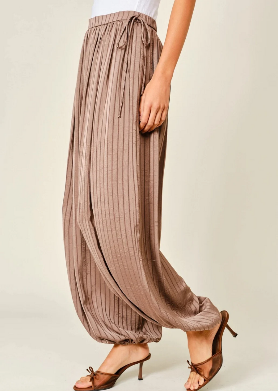 Soft satin striped fabric design
Elastic waistband for comfortable fit
Adjustable drawstring side details
Relaxed silhouette with easy movement
Comfortable bubble balloon pants shape
Lightweight flowy construction
Casual chic statement bottoms
Soft glossy satin texture finish
Functional everyday wear design
Perfect for stylish seasonal outfits