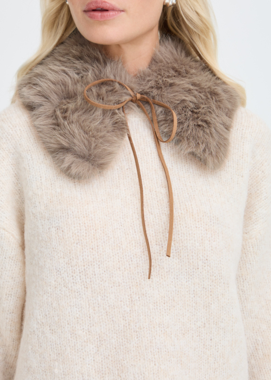 Elevate your cold-weather wardrobe with this statement faux fur collar. Designed to sit comfortably over your favorite knits and outerwear, it features a rich, touchably soft texture in a warm neutral shade. The slim front tie allows you to secure it effortlessly with a dainty bow, making it the perfect versatile accessory to instantly update simple tops, sweaters, and tailored coats throughout the season.