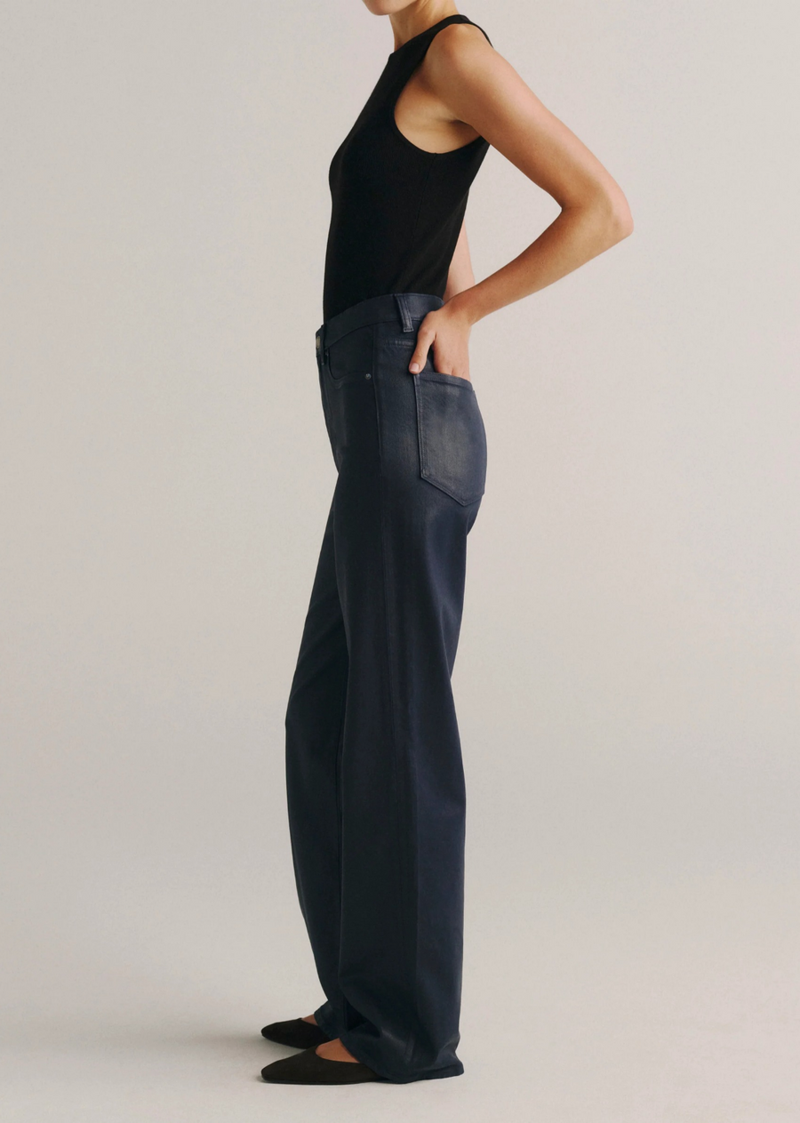 Karmine high-rise wide-leg jeans in deep navy blue coated denim with a leather-like finish, silver hardware, tonal stitching, a clean hem, and a black back patch. Designed with a flattering sculpted fit and a 32-inch inseam.