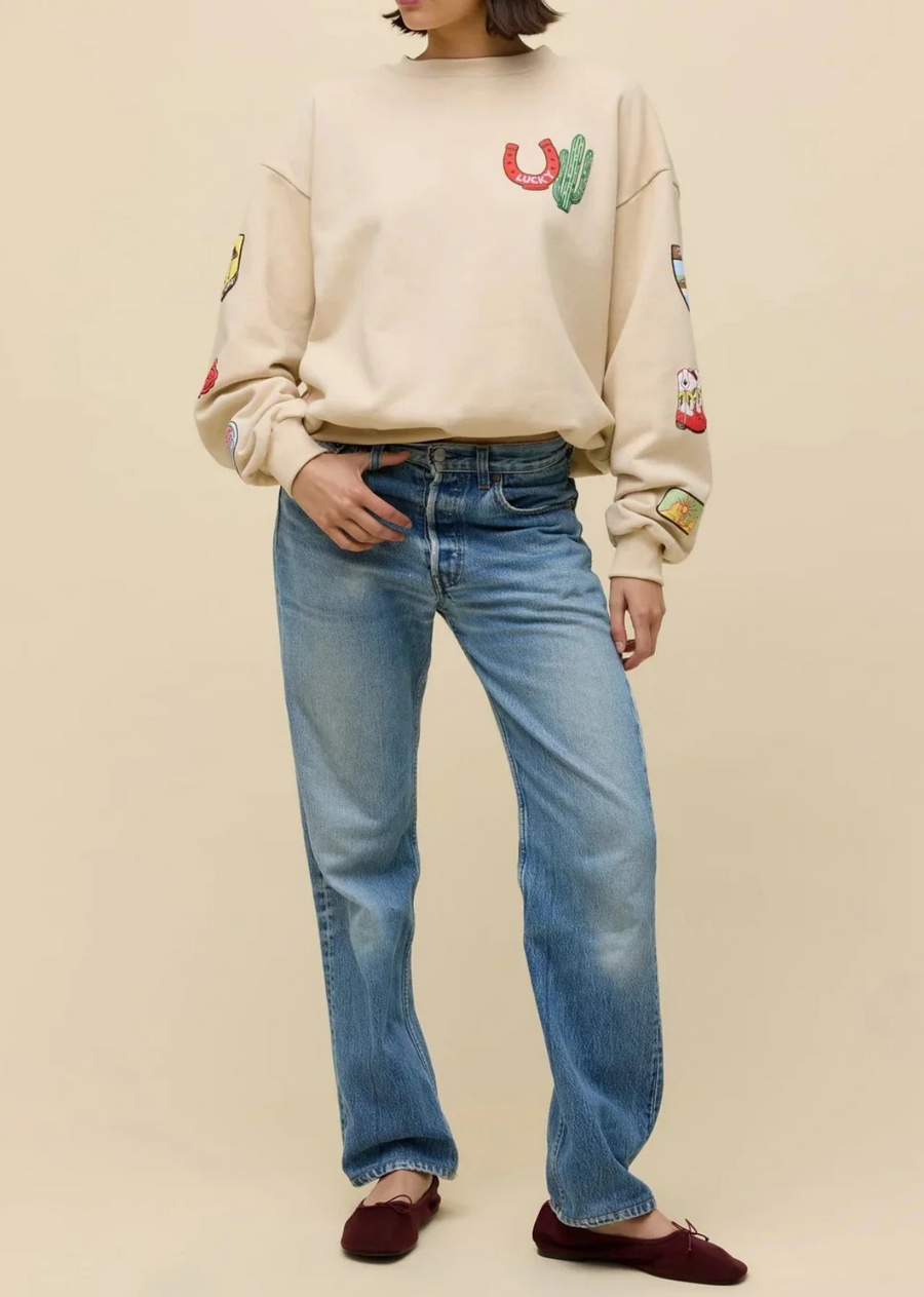 Add a touch of western charm to your casual wardrobe with this vintage-inspired graphic sweatshirt. Cut in a relaxed, relaxed-fit silhouette with dropped shoulders and classic ribbed trims, this cozy pullover features vibrant embroidered patches throughout. From a lucky horseshoe and Saguaro cactus on the chest to colorful cowboy boots, and western badges down the sleeves, every detail brings playful personality to an effortless off-duty look.