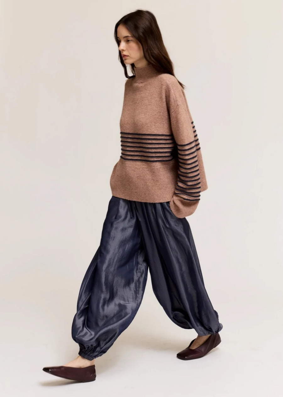 Make a bold statement with these contemporary dark navy barrel pants. Designed with a dramatic, voluminous silhouette, this piece features a relaxed fit through the legs that tapers neatly into gathered, cinched ankles for a striking modern shape. Crafted from a smooth fabric with a subtle sheen, they offer an avant-garde touch that pairs effortlessly with cozy knit sweaters or sleek fitted tops.