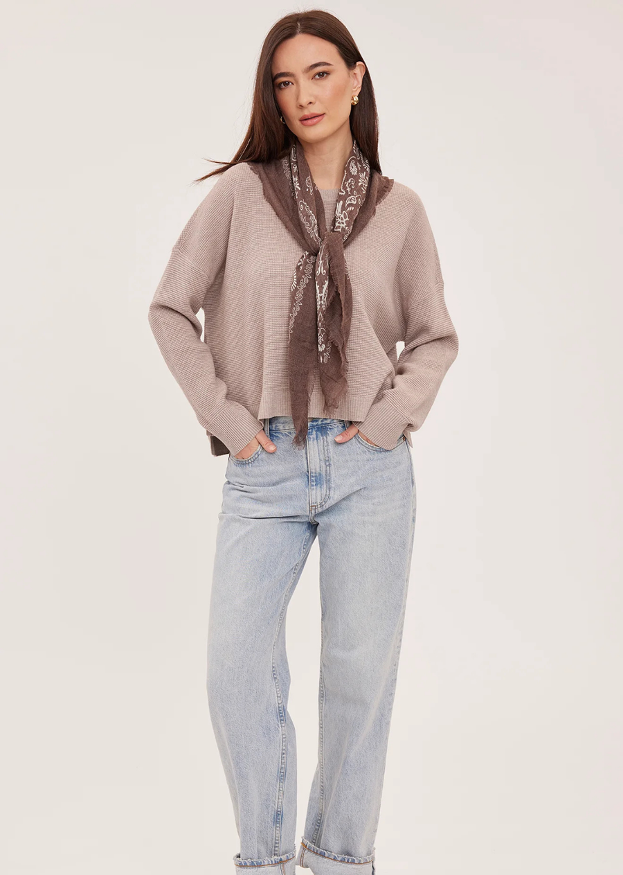 The Axel sweater is made of a soft yarn in a waffle knit pattern. Features include a crew neckline, exposed seam details, and side slits.