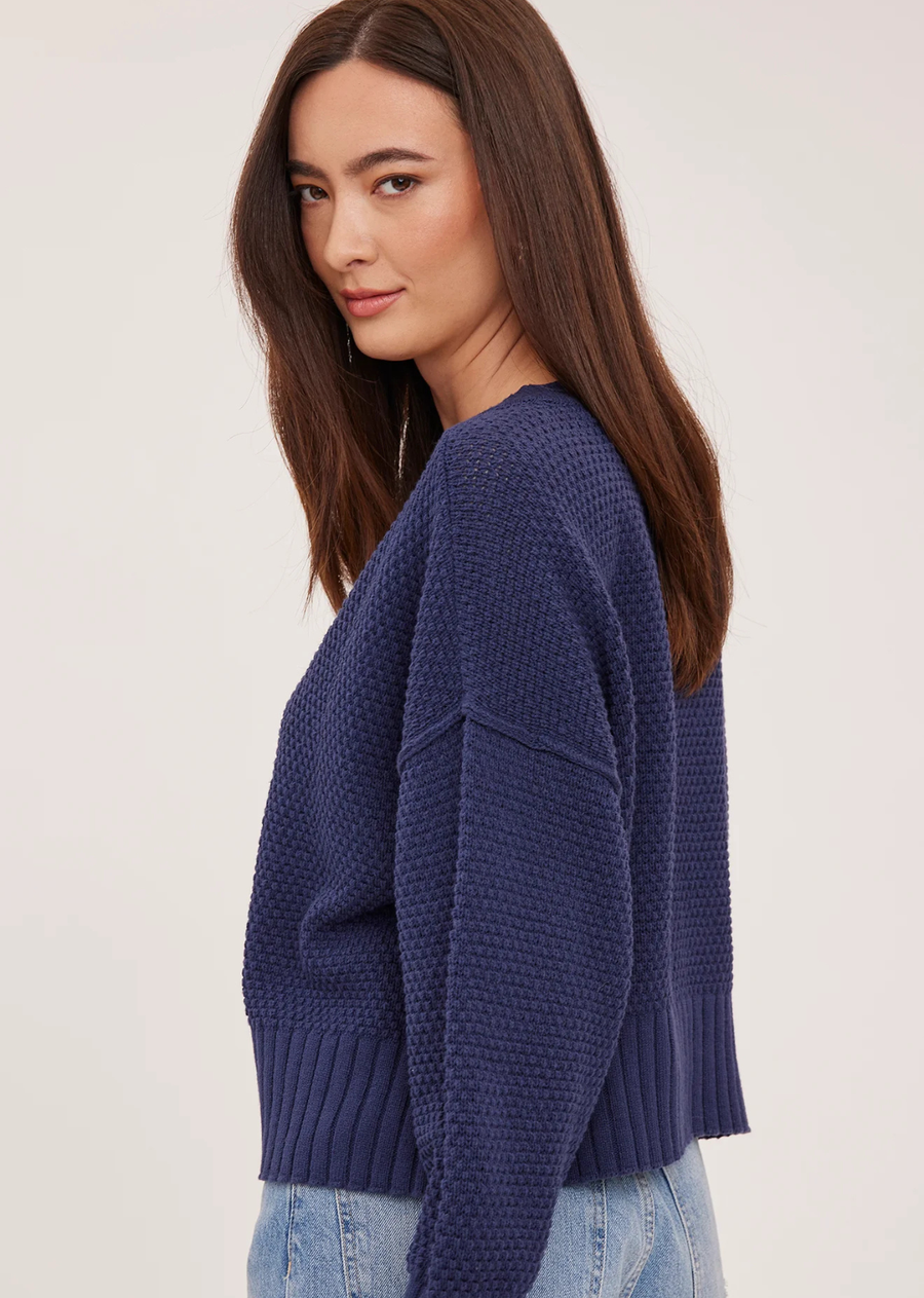 The Jennalee cardigan is made of a cotton blend yarn in a textured stitch pattern. Features include a front button closure and exposed seam details.