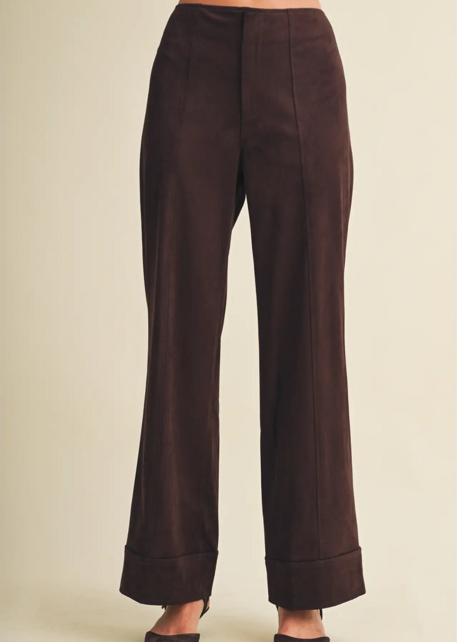 These high-waisted trousers are defined by a commanding wide-leg profile, engineered with a permanent pintuck seam for a sharp, clean line.

Crafted from a substantial woven faux suede, the material features a meticulously napped surface with a velvety hand-feel and a sophisticated matte luster. The fabric's stable construction ensures the form holds its shape, while a weighted, turned-up cuff anchors the silhouette for a structured finish.