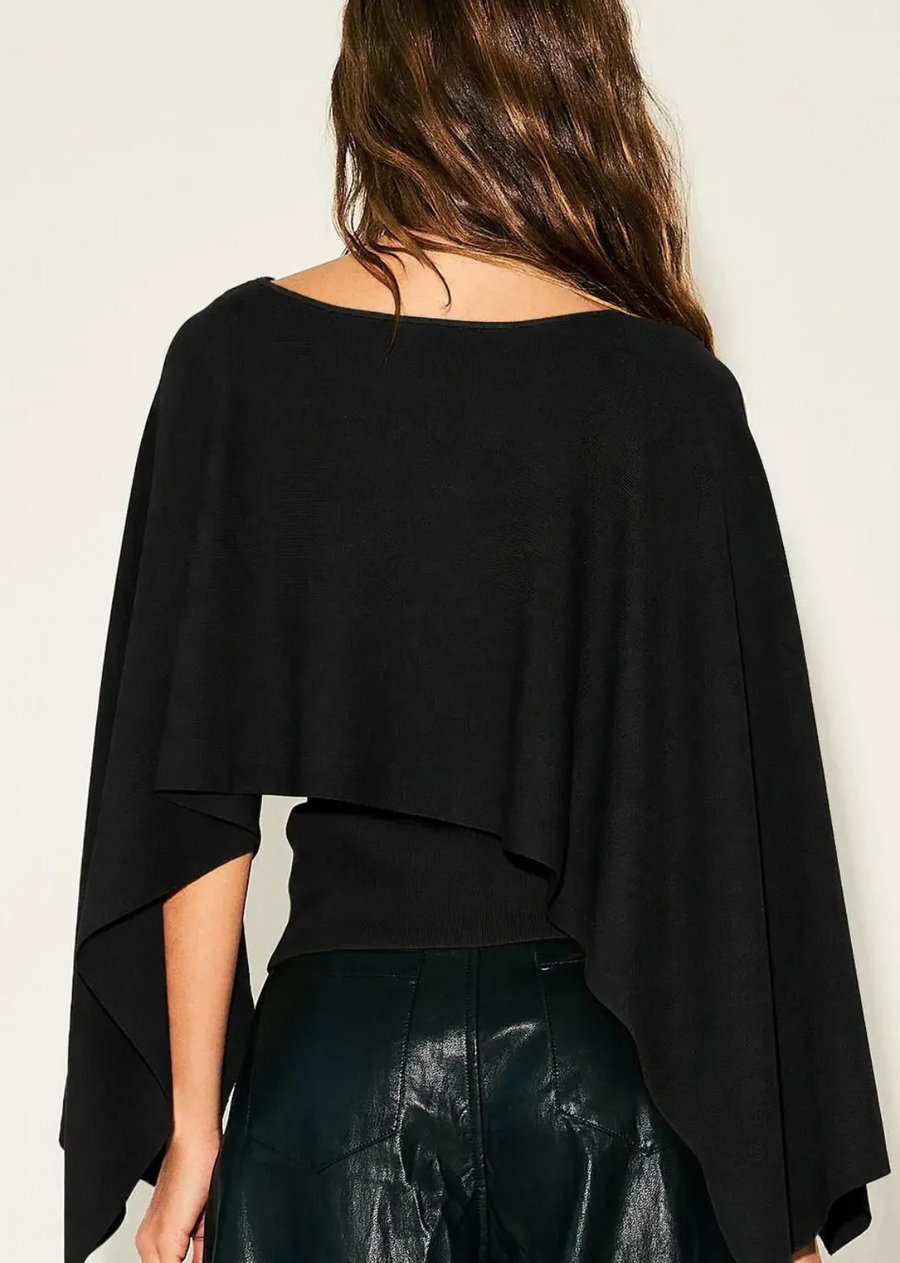 Elevate your transitional wardrobe with this cape overlay knit top. Designed with a chic layered construction, this piece features a fitted, sleeveless base paired with a dramatic, flowing caped overlay that drapes over the shoulders and arms for a striking silhouette. The soft, warm neutral tone makes it an exceptionally versatile piece to pair with everything from sleek faux-leather trousers to tailored skirts.