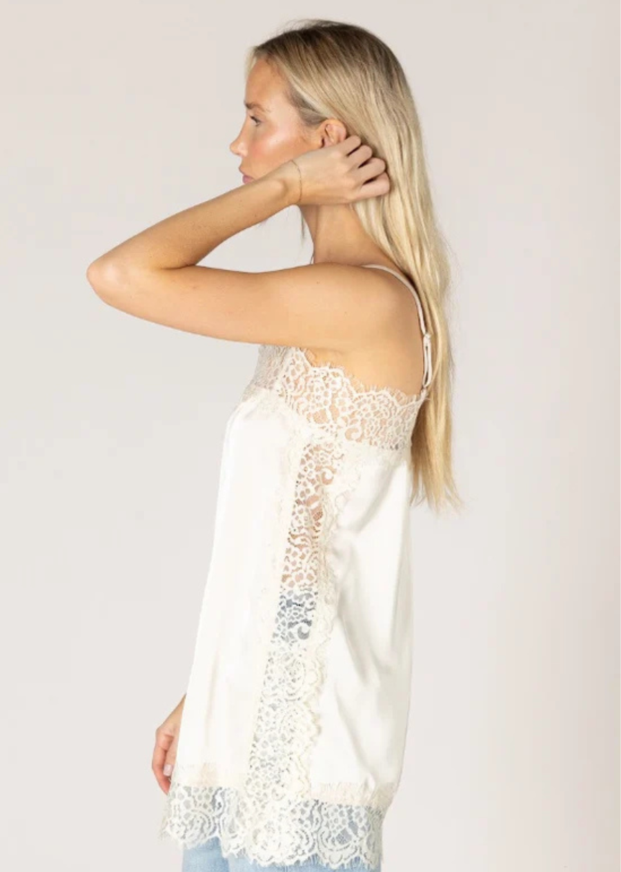 Elevate your everyday wardrobe with this effortlessly feminine satin cami. Designed with a relaxed, flowy silhouette, it features delicate lace trim along the neckline, hem, and sides for a romantic touch. Adjustable spaghetti straps provide the perfect fit, while the silky fabric drapes beautifully for an elegant look.&nbsp; This is the perfect layering piece to add to your collection, pair in under your sweater or wear a short/long sleeve under. Looks great with denim or a tailored trouser, perfect for bo