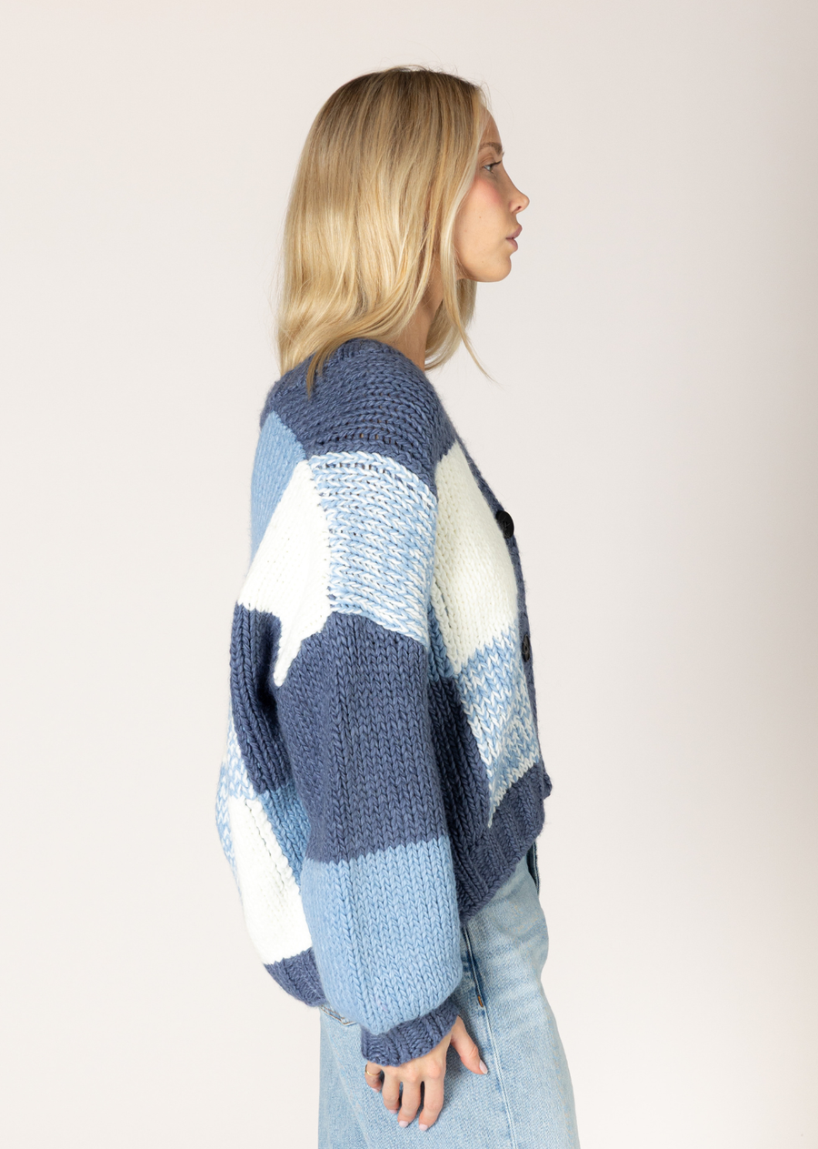 This v-neck cardigan features a unique blue denim graphic design, knit in a chunky yarn for that effortless, relaxed weekend look. This easy silhouette offers versatility, pairing perfectly with everything from your favorite jeans to sharp slacks. Crafted from a soft, easy-care yarn, it's the ideal piece for elevating your casual ensembles.