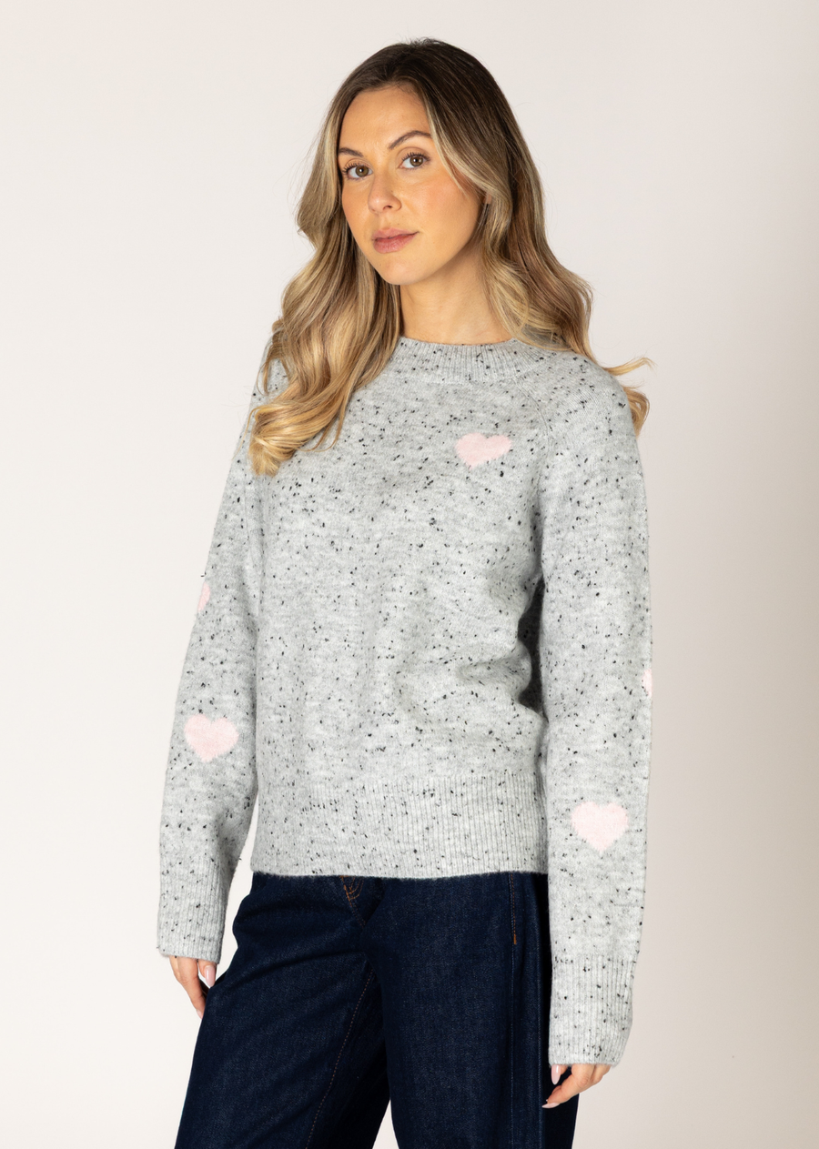 This pullover brings a playful touch to your wardrobe with its light grey base and charming pale pink heart design. This cozy, fitted pullover combines comfort with a pop of personality, making it a perfect choice for both casual and dressed-up looks.