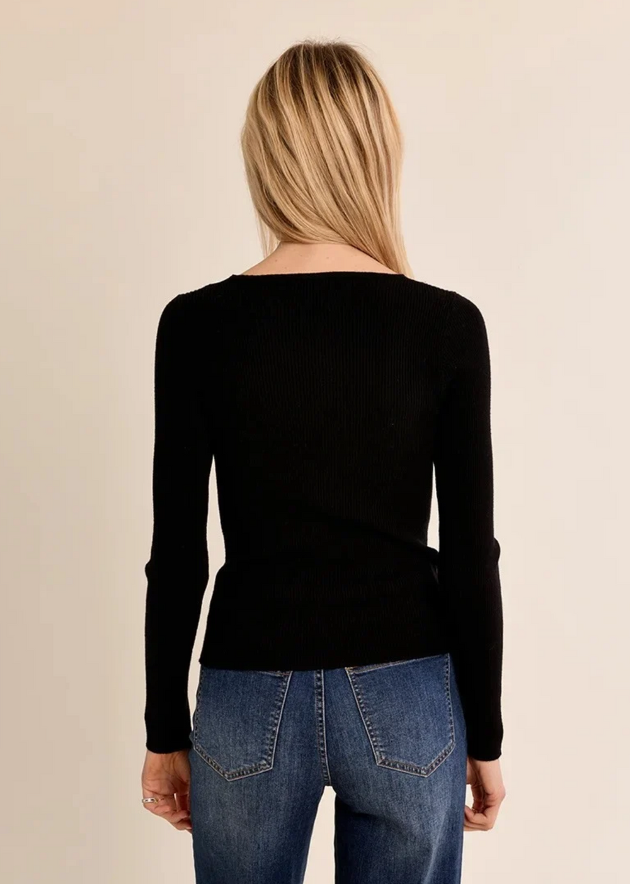 A timeless wardrobe staple with a delicate feminine touch, this long-sleeve knit top is cut from a finely ribbed black fabric that softly hugs the silhouette. It features a flattering V-neckline framed with intricate tonal eyelash lace trim, adding subtle elegance to an everyday favorite.