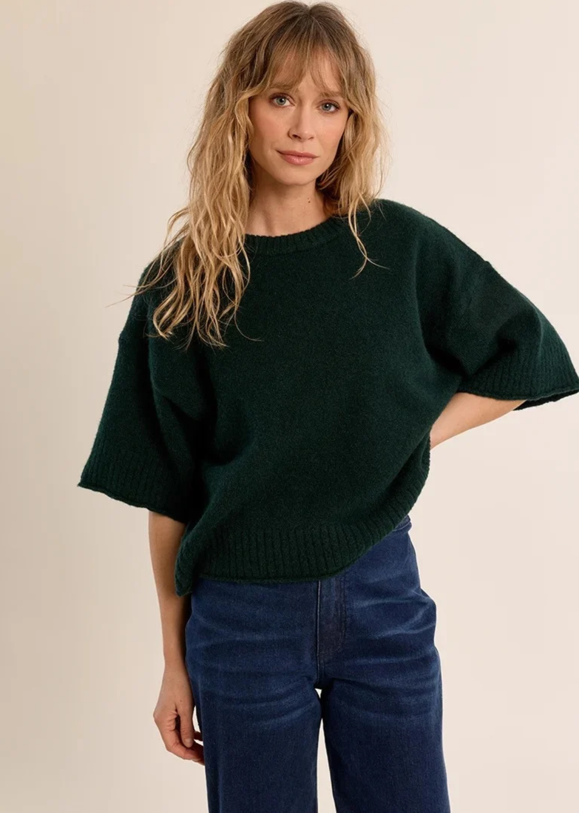 A chic, unexpected twist on classic knitwear, this short-sleeve sweater comes in a rich forest green hue. Crafted from a plush, fuzzy knit yarn, it features an oversized, relaxed silhouette with dramatic dropped shoulders and wide, elbow-length sleeves. Classic ribbed trimming along the crew neckline, wide cuffs, and hem adds subtle structured definition to the effortless drape.