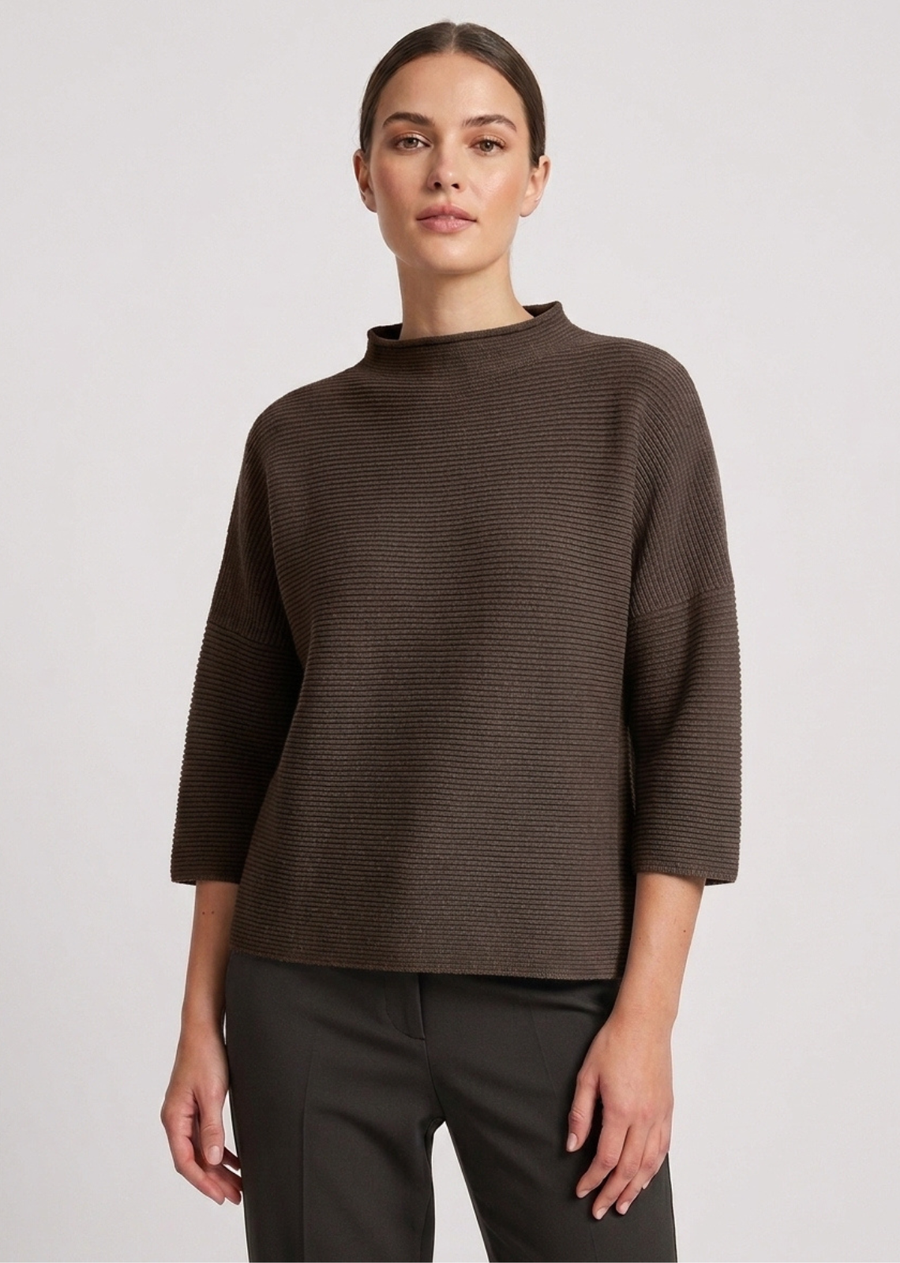 A modern mock-neck knit sweater in a rich forest green tone, featuring a clean horizontal rib texture and relaxed silhouette. Designed with dropped shoulders and modified three-quarter length sleeves, this piece offers a boxy, contemporary drape perfect for effortless layering.