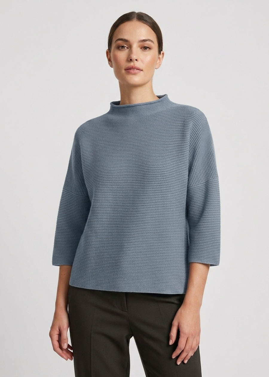 A modern mock-neck knit sweater in a rich forest green tone, featuring a clean horizontal rib texture and relaxed silhouette. Designed with dropped shoulders and modified three-quarter length sleeves, this piece offers a boxy, contemporary drape perfect for effortless layering.