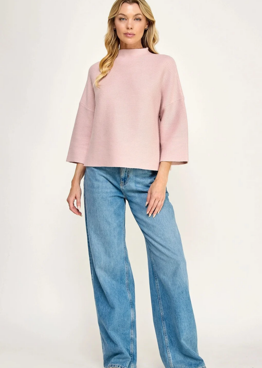 A modern mock-neck knit sweater in a rich forest green tone, featuring a clean horizontal rib texture and relaxed silhouette. Designed with dropped shoulders and modified three-quarter length sleeves, this piece offers a boxy, contemporary drape perfect for effortless layering.