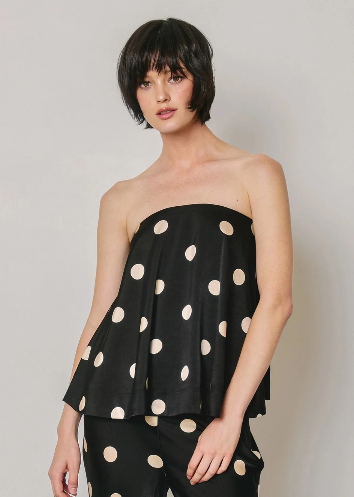 This strapless top features a relaxed, flowy silhouette with a timeless polka dot print for an effortlessly chic look.

Designed with an elasticized back and self-tie detail, it offers a comfortable fit while adding a playful, feminine touch. Model is 5'9" and wearing size Small.