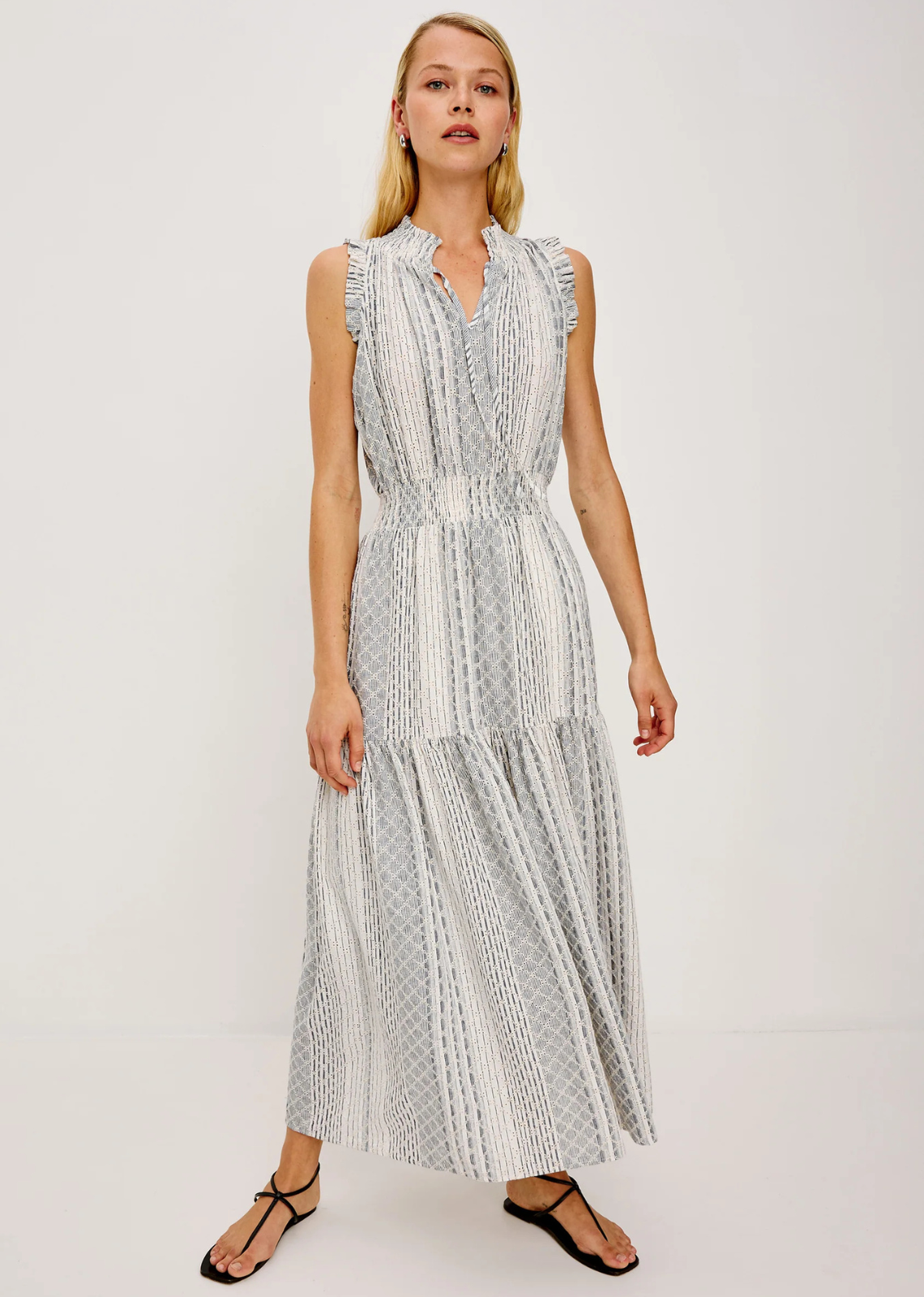The Alessi is a luxe, lightweight linen midi dress with a relaxed fit, a split V-neckline with self-ties, a smocked waist, ruffle trim, and full lining.