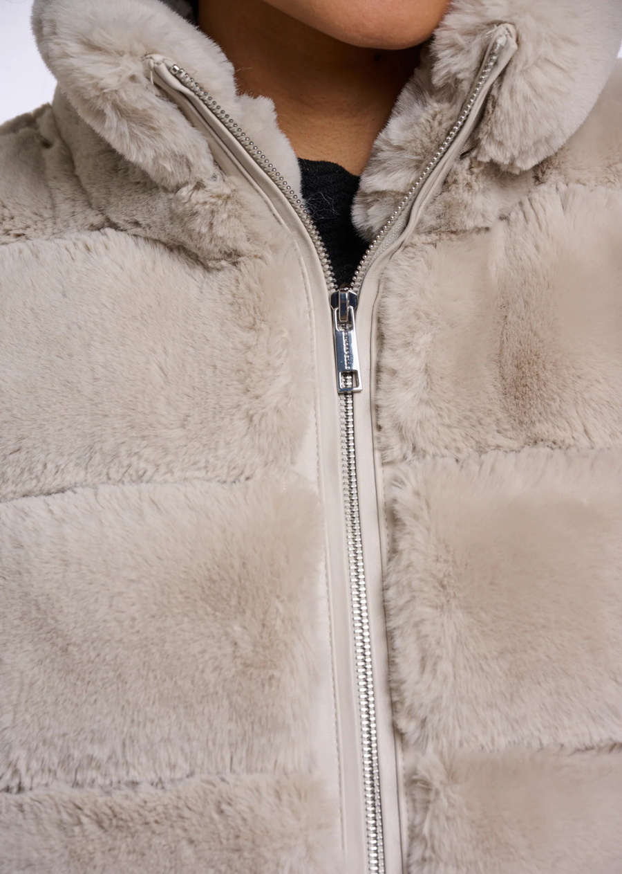 A faux fur waistcoat with a relaxed sleeveless silhouette, designed for effortless layered styling. The tactile finish adds depth to everyday looks, while the clean shape makes it easy to wear over knitwear, blouses or long-sleeve tops through the season.