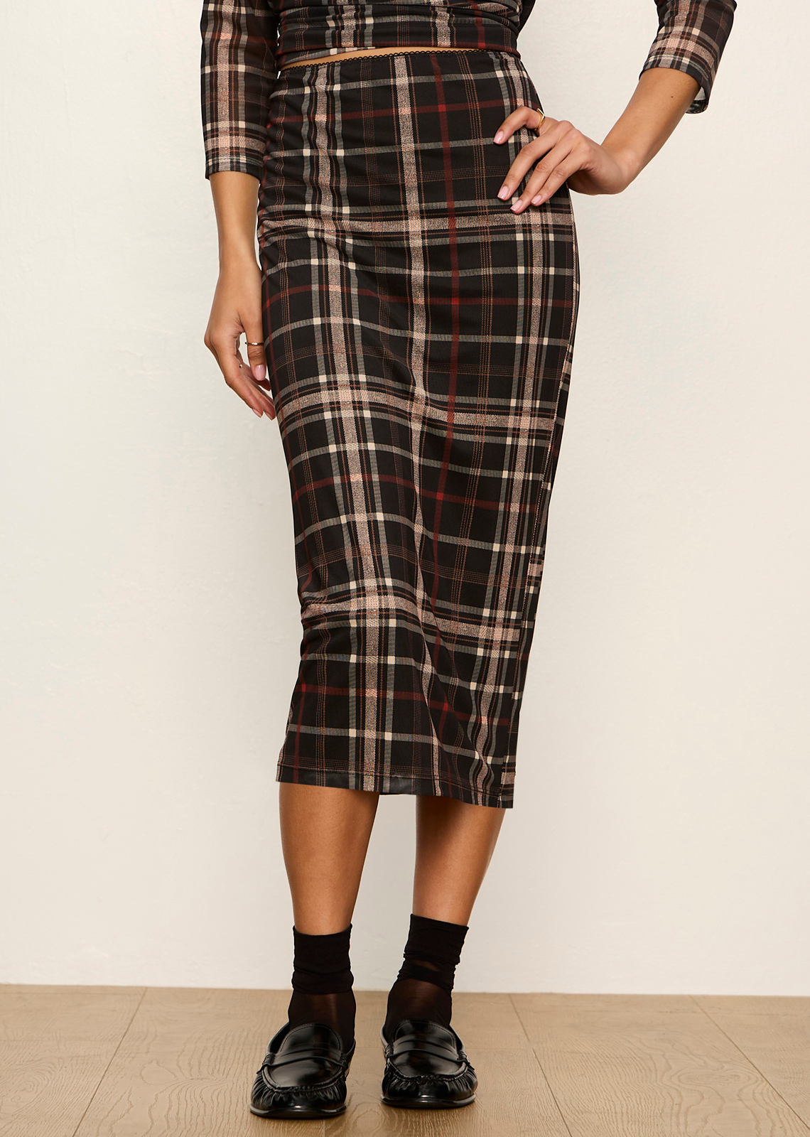 This midi pencil skirt offers a modern, dark-prep twist on classic menswear plaid. Crafted in a lightweight, semi-sheer mesh print overlay with stretch, it delivers a body-skimming profile that bridges casual daytime sophistication with edgy evening style.