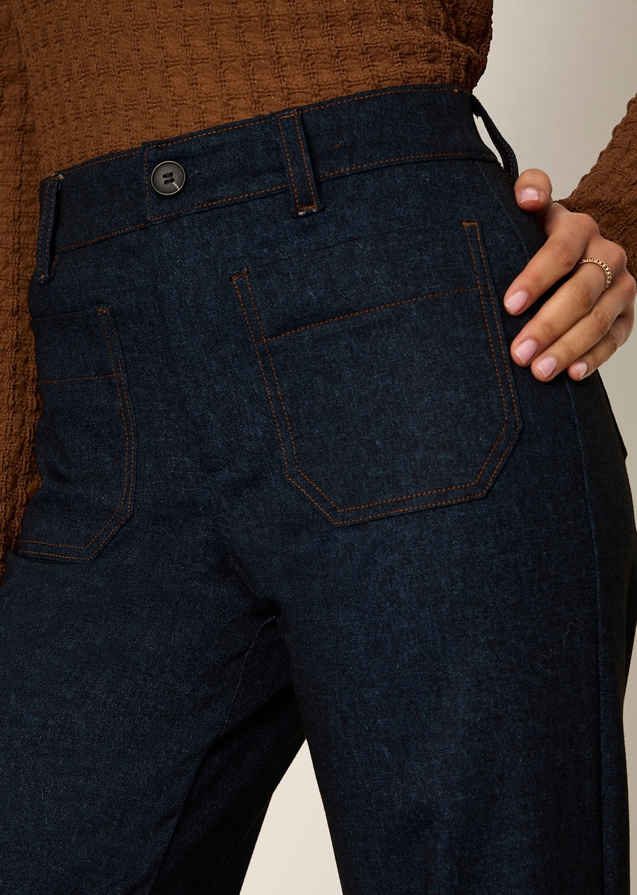 These dark-wash denim trousers offer a vintage, '70s-inspired aesthetic updated with modern, elevated tailoring. Combining the structure of polished dress trousers with the casual versatility of denim, they feature a sleek high-rise waist and straight leg silhouette.