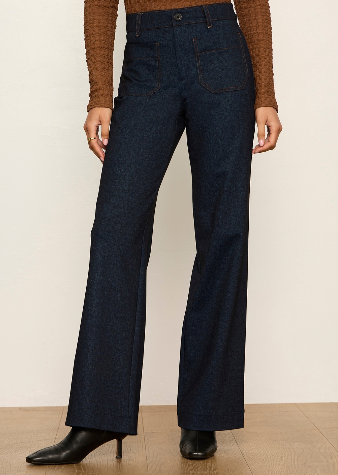 These dark-wash denim trousers offer a vintage, '70s-inspired aesthetic updated with modern, elevated tailoring. Combining the structure of polished dress trousers with the casual versatility of denim, they feature a sleek high-rise waist and straight leg silhouette.