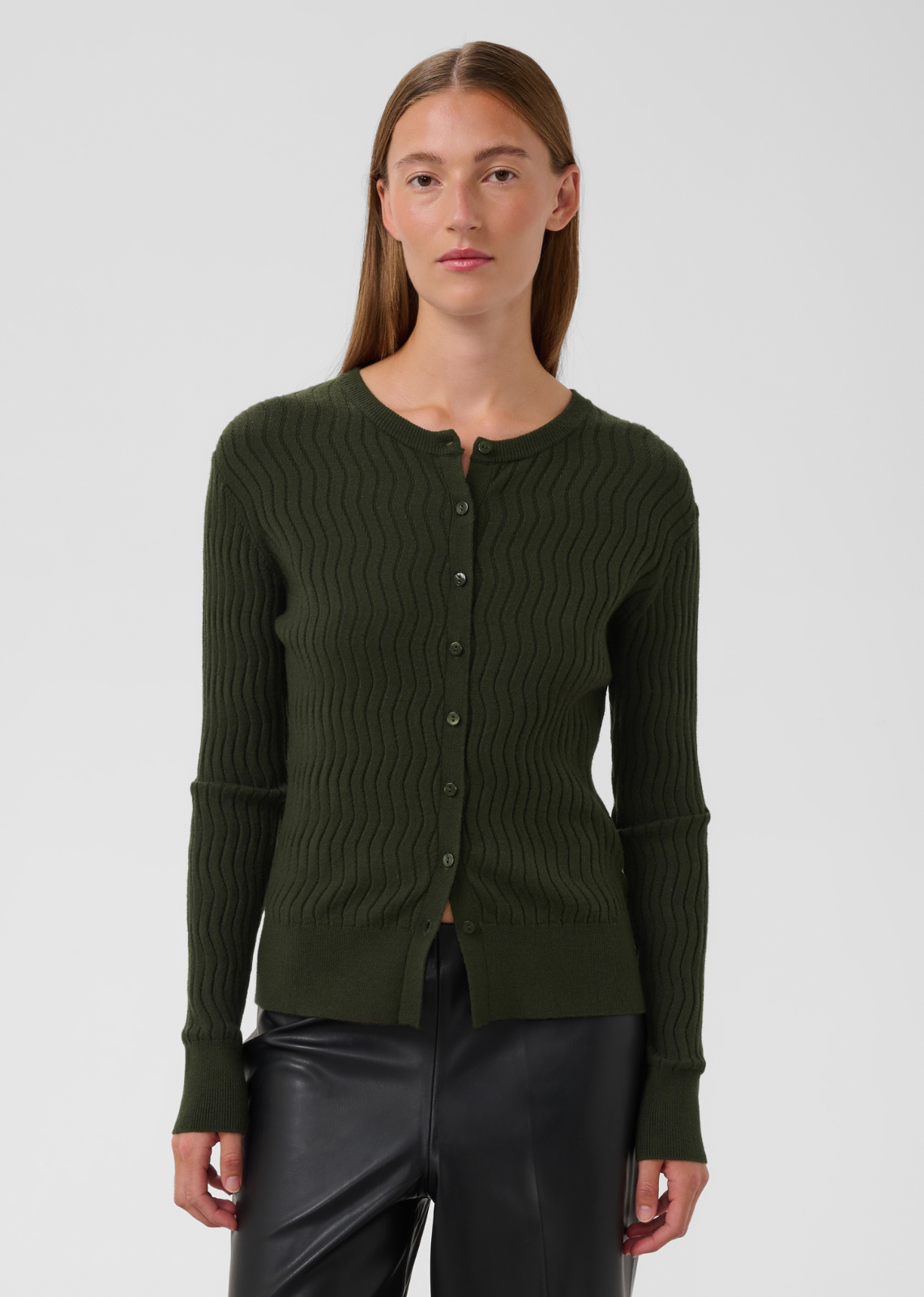 Bring subtle texture and polished charm to your capsule wardrobe with this button-down cardigan in rich forest green. Combining a classic silhouette with a modern, wavy ribbed finish, it offers a versatile piece that transitions seamlessly from day to night.
