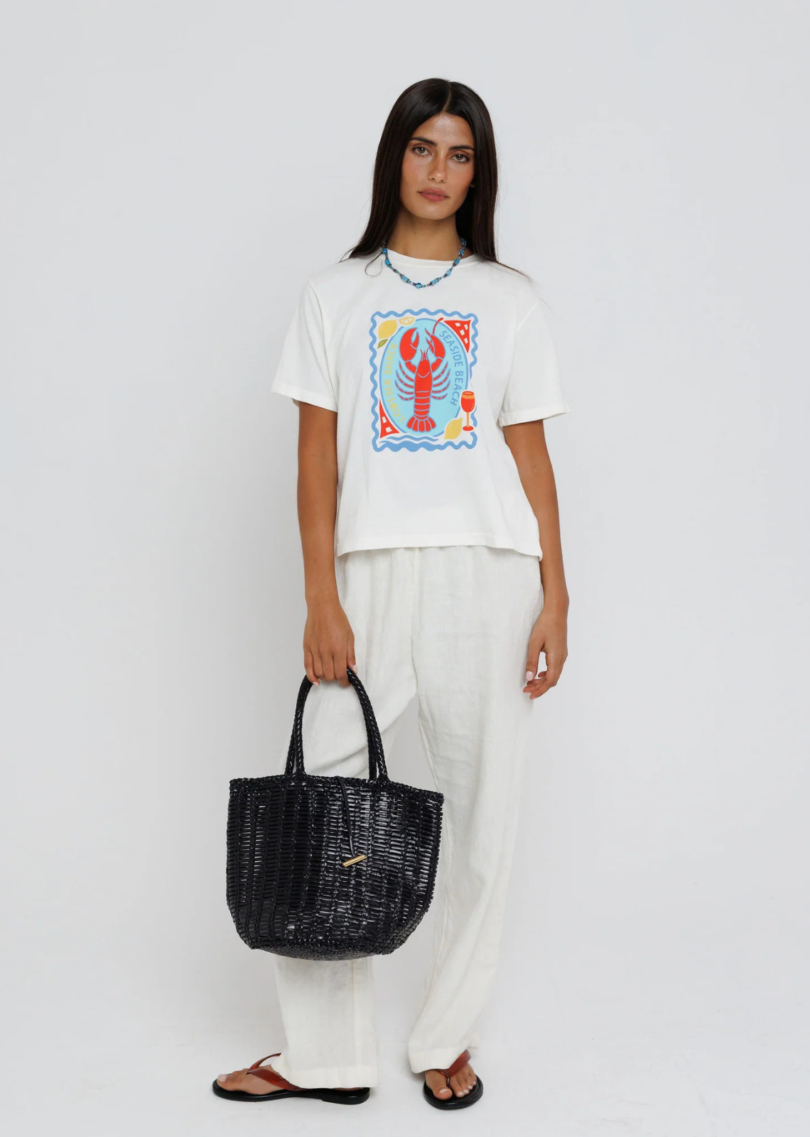 Bring a splash of coastal charm to your everyday wardrobe with this playful graphic tee. Featuring a vibrant lobster illustration framed by seaside-inspired details in bold shades of blue, red, and yellow, this relaxed tee captures the carefree spirit of summer. Finished with a classic crew neckline and an easy fit, it's the perfect piece to pair with linen pants, denim, or your favorite shorts for effortless warm-weather style.