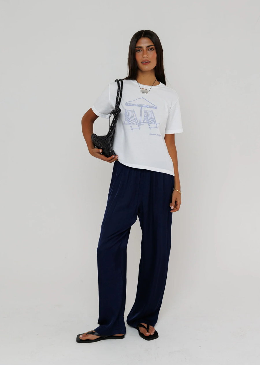 Easy, effortless, and made for sunny days, this graphic tee features a minimalist beach scene with two striped lounge chairs beneath a seaside umbrella. Its clean line-art design adds a subtle coastal touch, while the relaxed fit and classic crew neckline make it an everyday essential. Pair it with linen pants, denim, or shorts for an effortlessly laid-back summer look.