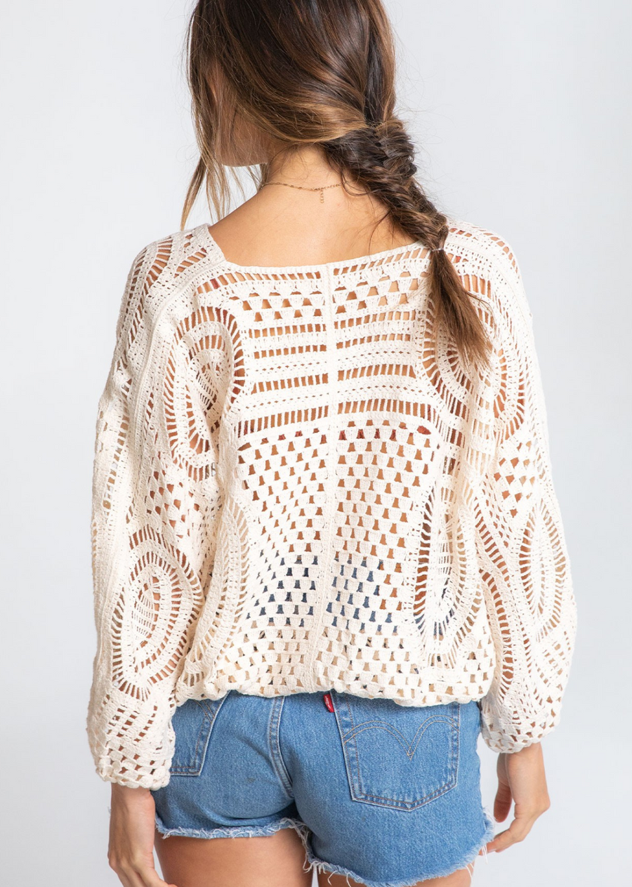 Sunrise Crochet Wrap Top. The possibilities are endless with this classic bohemian crochet-knit top. Featuring voluminous long sleeves, a surplice wrap front, and&nbsp;an elastic hemline. We love to throw this effortless style over our swimsuit at the beach for a quick cover-up, or styled over a cami with jean shorts.