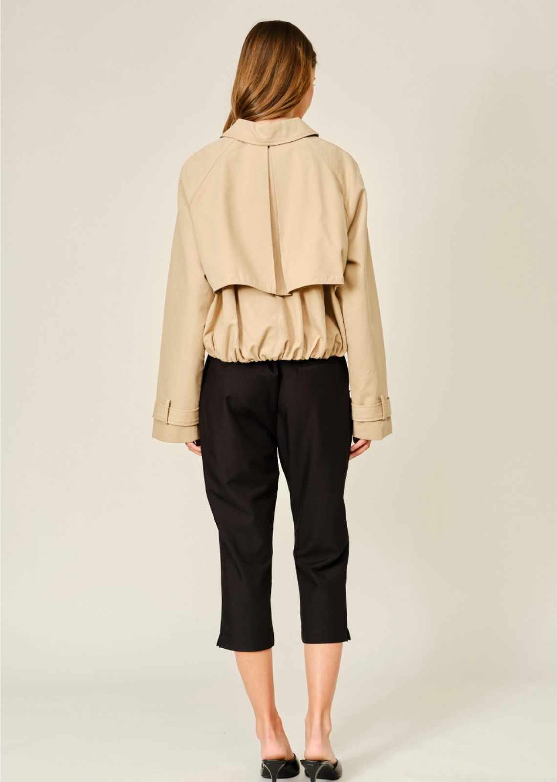 Modern half trench coat featuring a convertible collar, layered front flap, structured silhouette, and elasticized hem.
