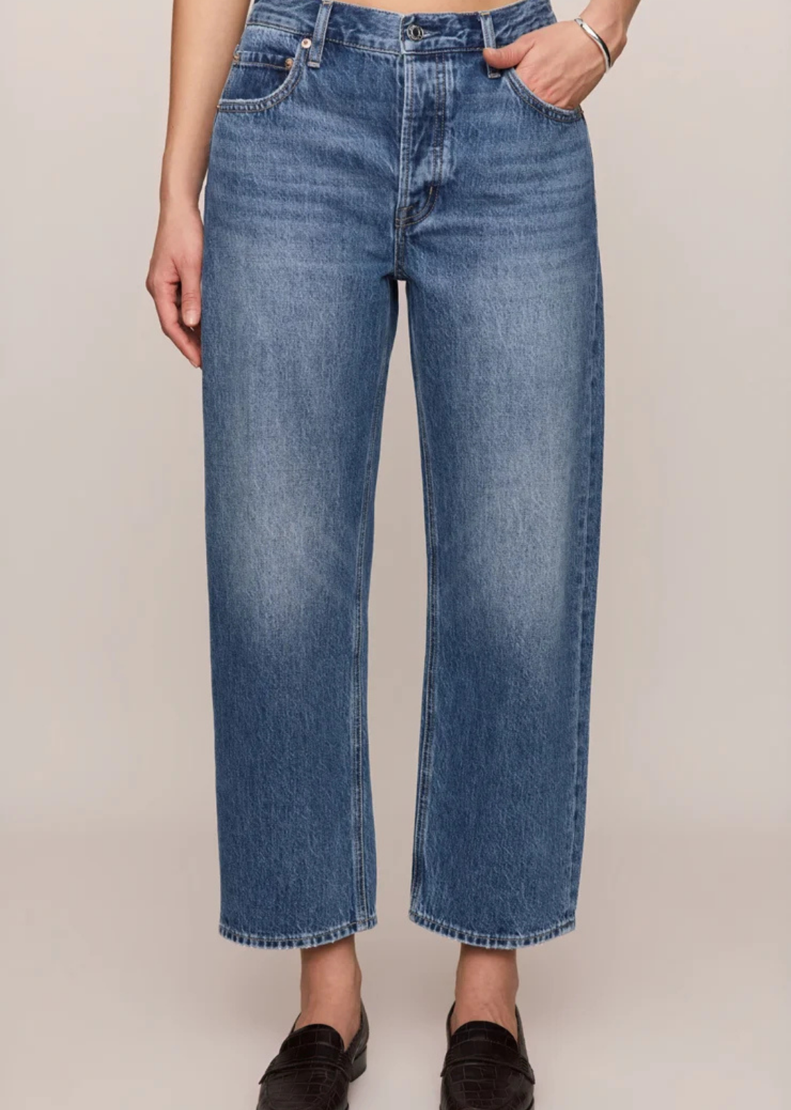 Vintage-wash mid-rise jeans featuring a relaxed bowed-leg silhouette, ankle-length hem, and classic five-pocket design in 100% cotton denim.



