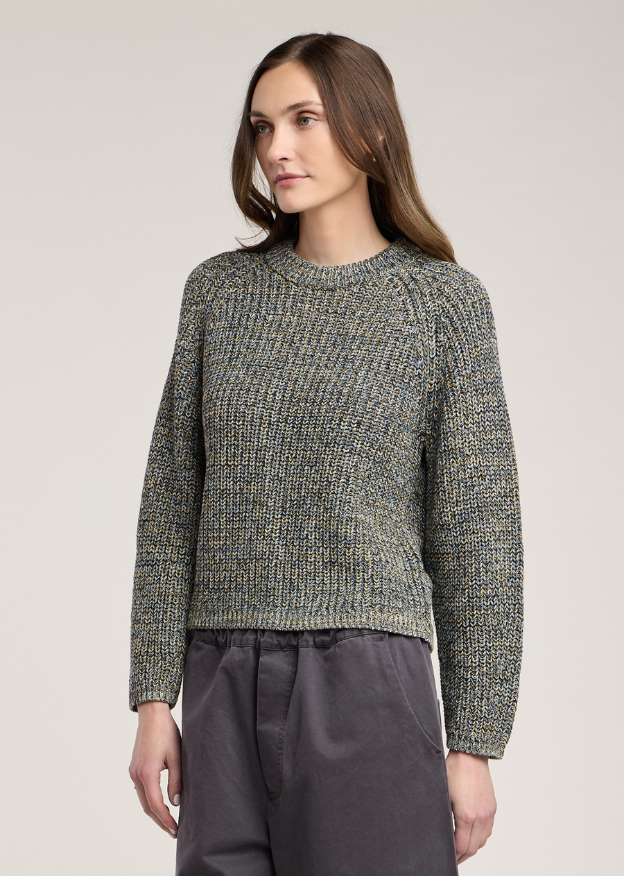 This cozy crewneck sweater offers a rich, tactile design crafted from a chunky pima cotton knit in a dynamic marled blend. The fabric features a tight rib-like stitch that beautifully intertwines muted shades of slate blue, earthy mustard yellow, and off-white yarn, giving the sweater a multi-dimensional, textured appearance. Designed with a classic crew neckline and flattering raglan-style sleeves, it features a slightly cropped, boxy silhouette that falls neatly at the high waist. Ribbed trimming along th