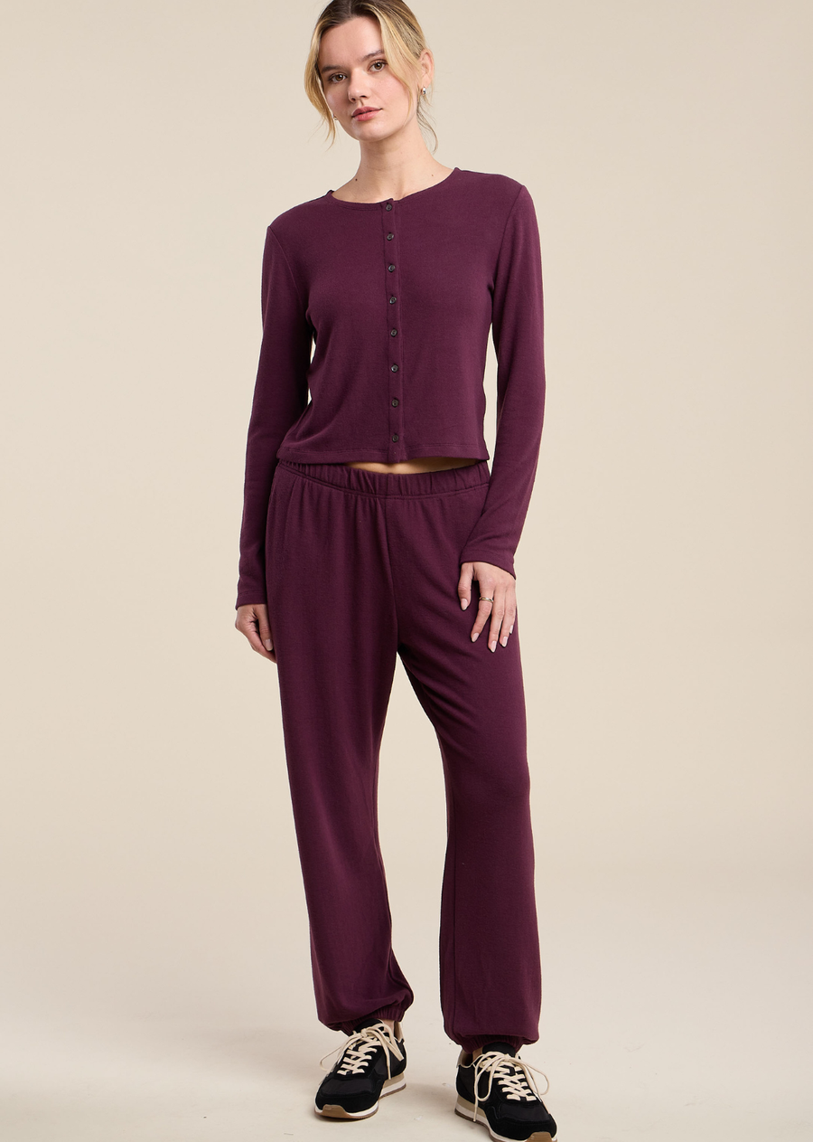 These ultra-soft jogger pants are rendered in a deep, rich dark plum shade, offering a luxurious update to everyday loungewear. Crafted with a comfortable elasticated waistband, they feature a relaxed fit through the leg that gathers neatly into elasticated cuffs at the ankle. Functional side slash pockets enhance their casual practicality, while the lightweight, cozy knit fabric ensures smooth draping.