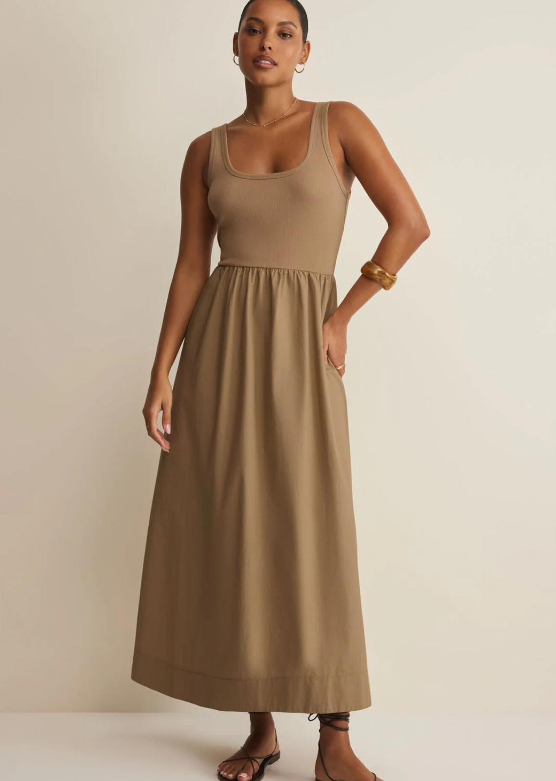 This sleeveless maxi dress blends a fitted ribbed bodice with a full gathered cotton poplin skirt. Lightweight and feminine, it moves beautifully through summer days and nights.