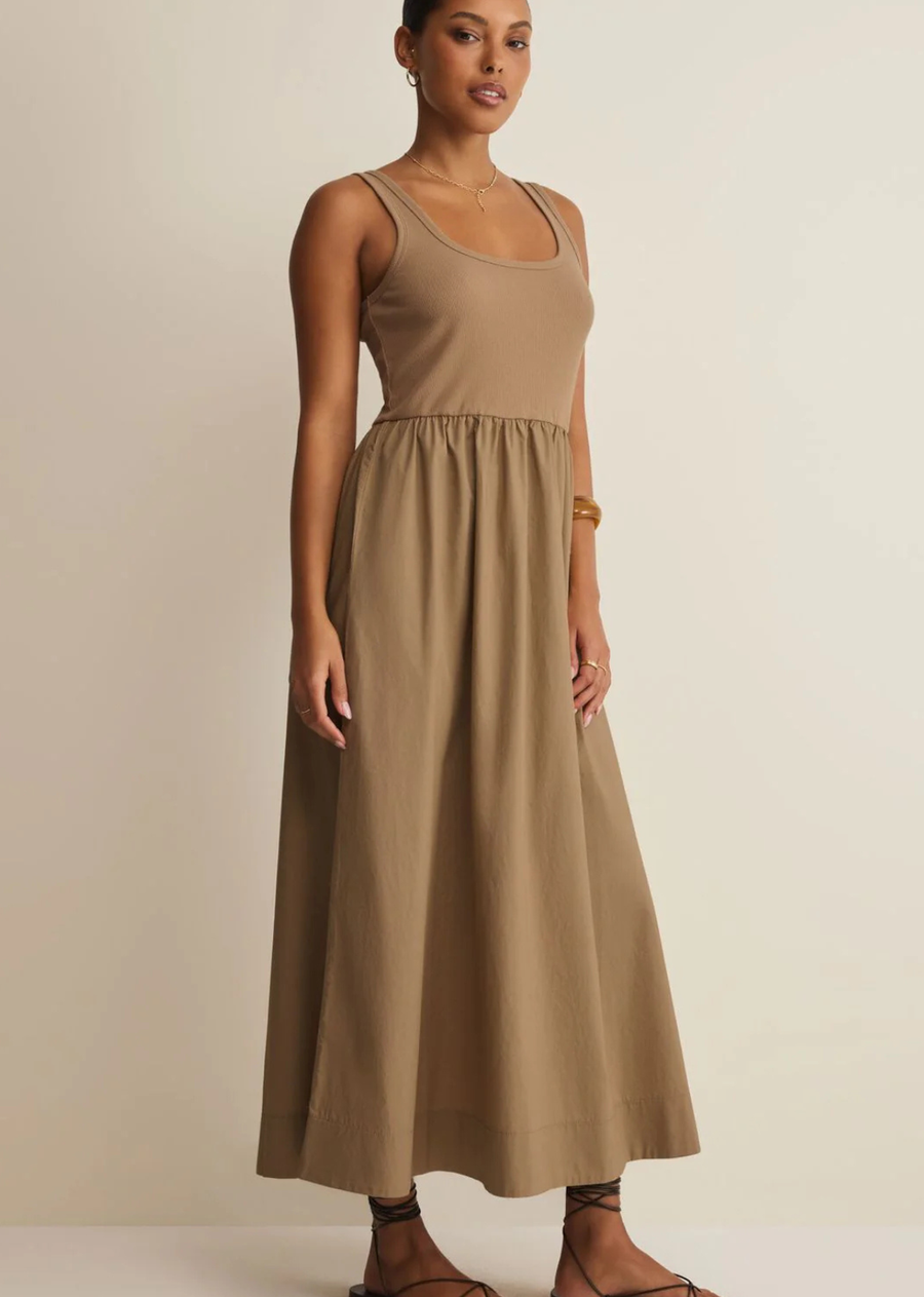 This sleeveless maxi dress blends a fitted ribbed bodice with a full gathered cotton poplin skirt. Lightweight and feminine, it moves beautifully through summer days and nights.