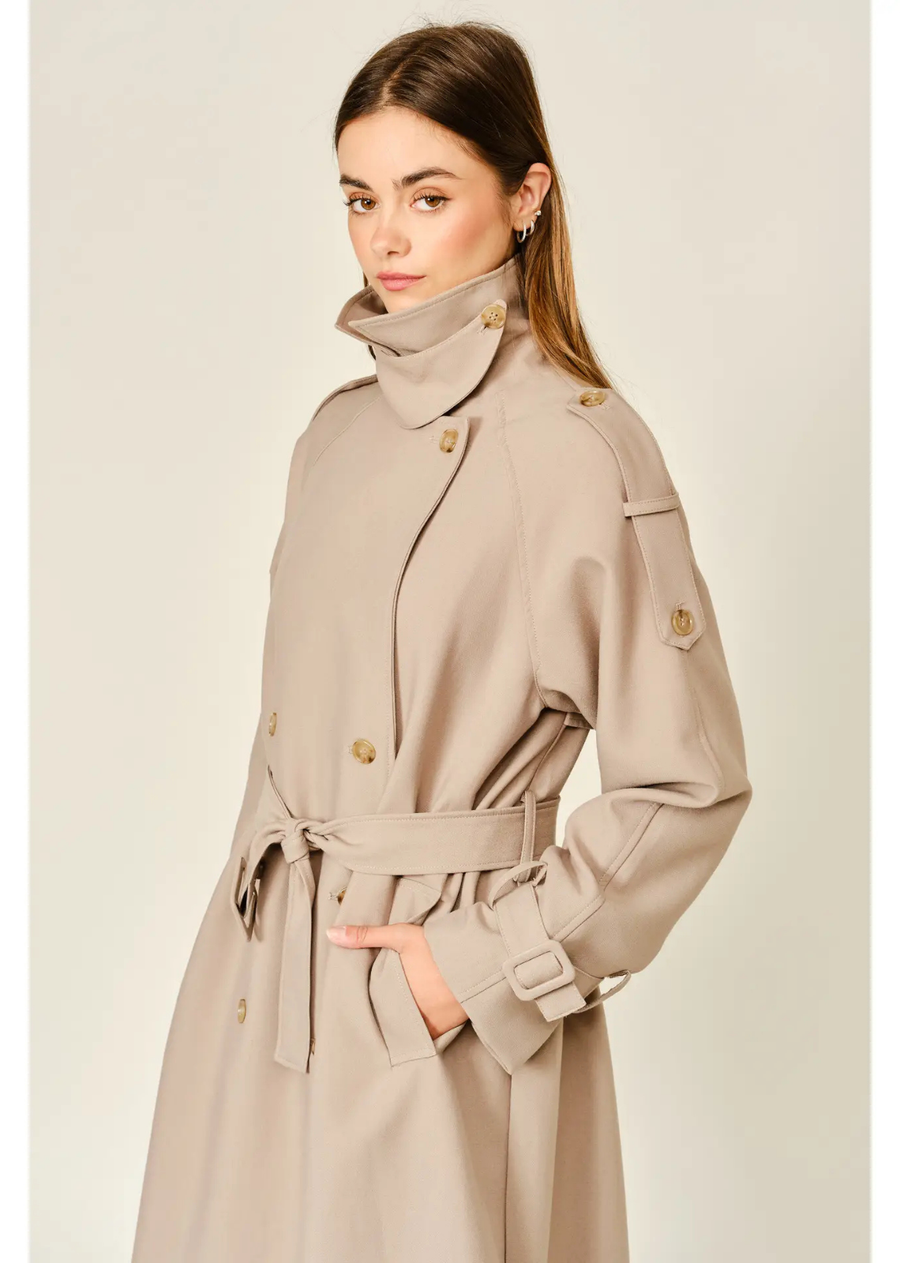 Tan longline trench coat with a relaxed fit, layered neckline, double-button closure, and adjustable waist belt.