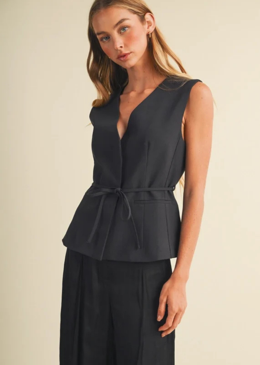 Structured suiting top with a deep V-neckline, contoured seams, removable waist tie, peplum hem, and extended shoulders.