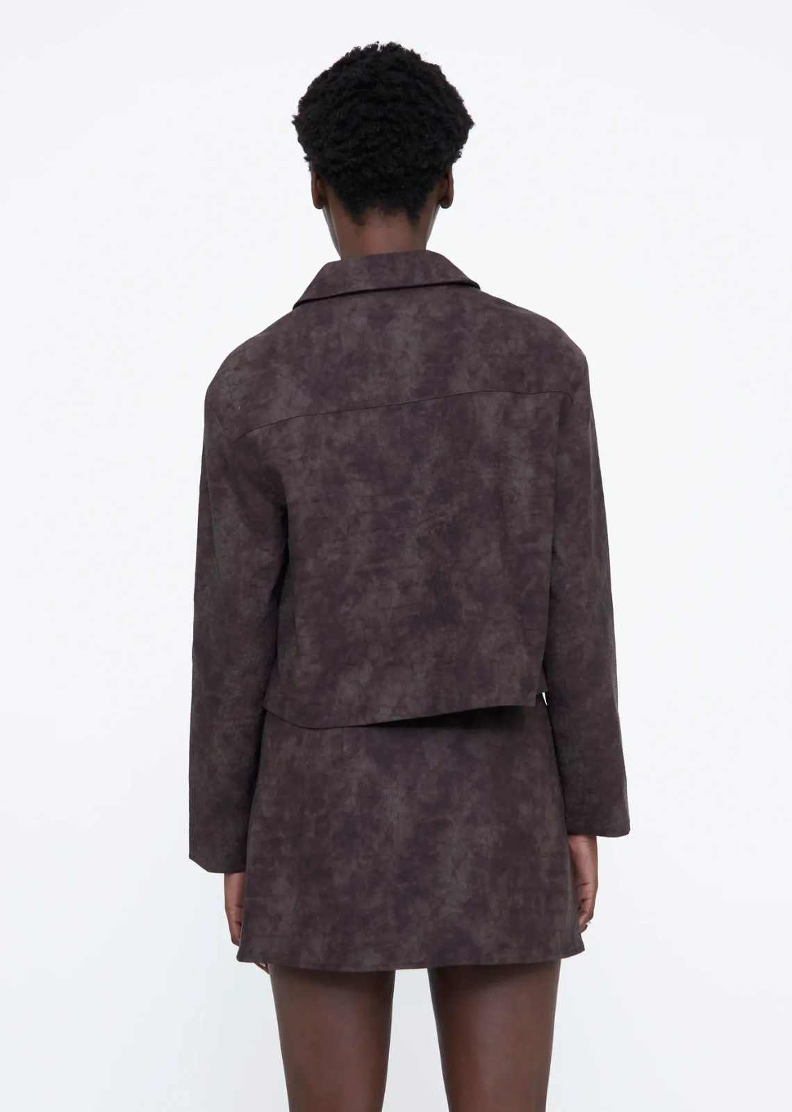 Brown faux leather jacket with a lapel collar, long sleeves, slightly dropped shoulders, front zip closure, and inner lining.