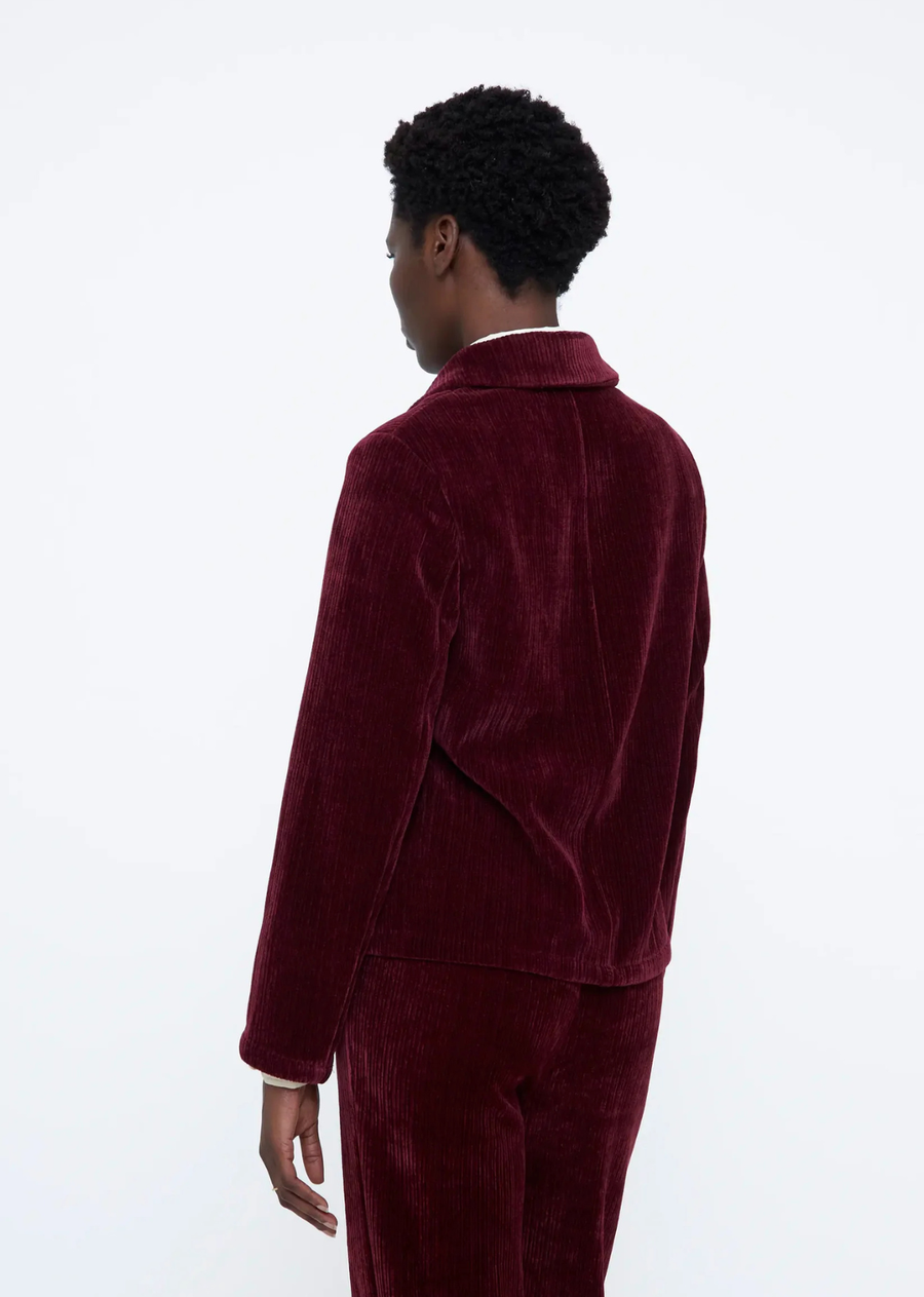 Burgundy velvet blazer with a lapel collar, long sleeves, front button closure, front pockets, and inner lining.