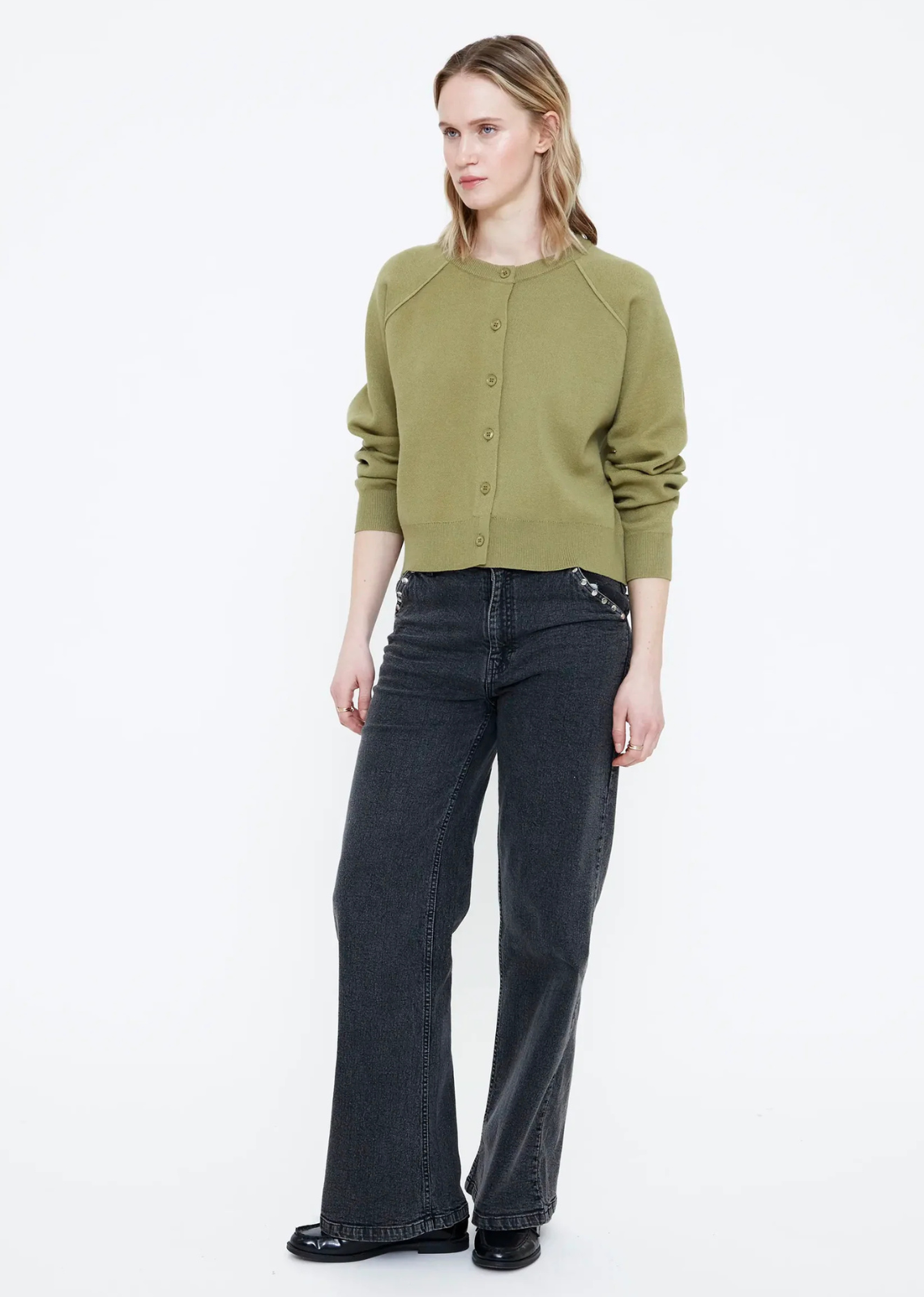 Green knit cardigan with a round neckline, long sleeves, dropped shoulders, matching green buttons, and ribbed trims.
